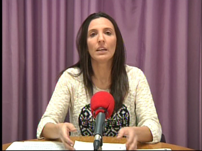 Persona hablando en una conferencia de prensa frente a un micrófono rojo.