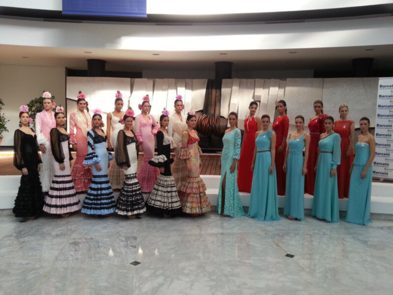 Desfile de trajes de flamenca con modelos en una pasarela.