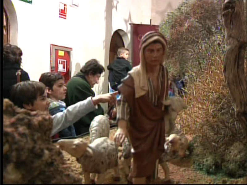 Figura de pastor con ovejas en escena navideña, rodeado por niños curiosos.