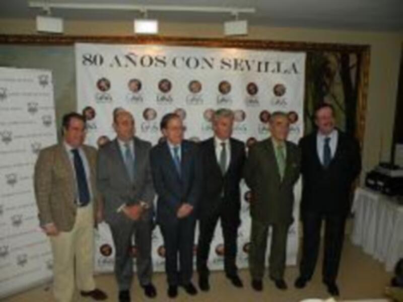 Celebración del 80º aniversario de Sevilla con una reunión de hombres en trajes formales.