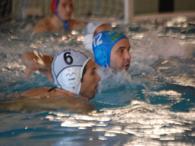 Jugadores de waterpolo en acción durante un partido en una piscina.