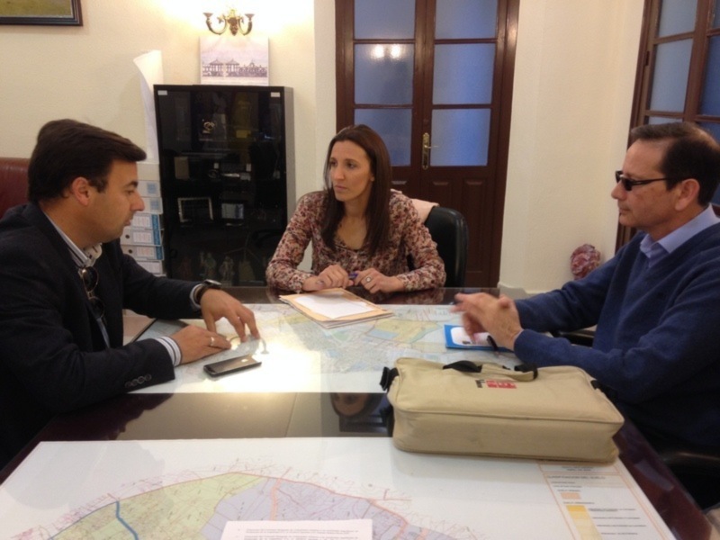 Reunión de trabajo en una oficina, discutiendo sobre documentos y mapas.