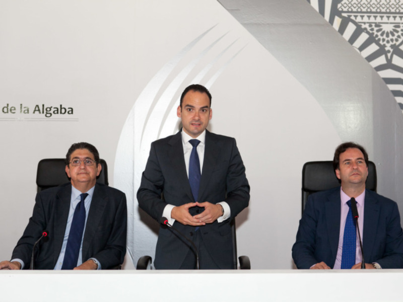 Tres hombres en trajes de negocios en una conferencia o reunión formal.
