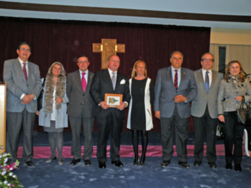 Premiación en un evento formal con un grupo de personas posando junto a un premio.