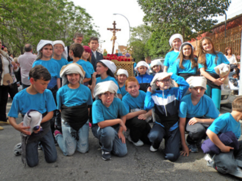 Jóvenes con trajes tradicionales posando en una procesión religiosa al aire libre.