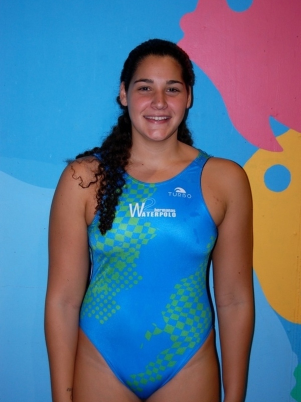 Retrato de una nadadora en traje de baño de waterpolo frente a un fondo azul con motivos geométricos.