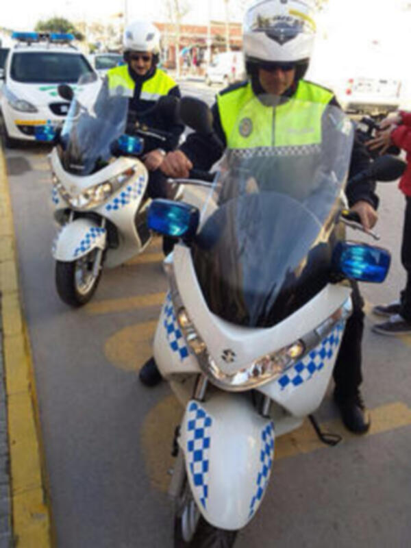 Oficiales de policía en motocicletas patrullando una calle urbana.