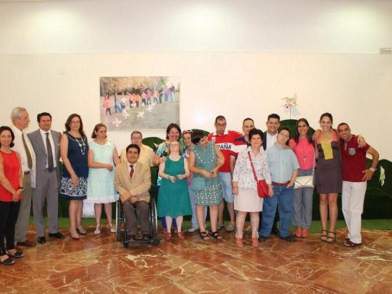 Grupo de personas posando para una foto en un espacio interior, con una pintura al fondo y un ambiente formal.
