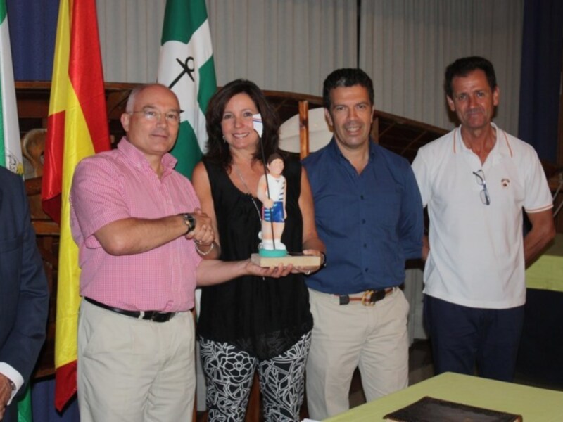 Entrega de reconocimiento en evento oficial con banderas y trofeo.