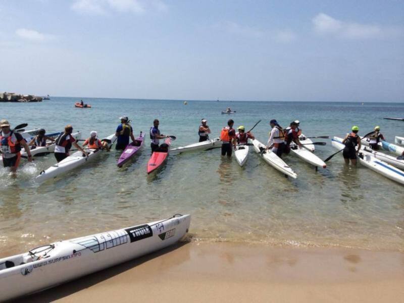 Equipo de kayaks listos para comenzar una carrera en la playa.