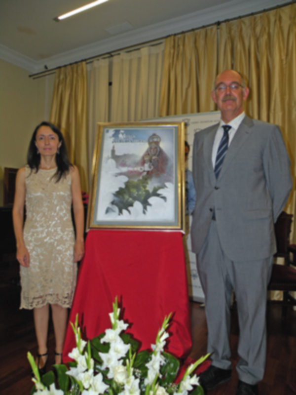 Presentación de una obra de arte en un evento formal con dos personas posando junto a una pintura enmarcada.
