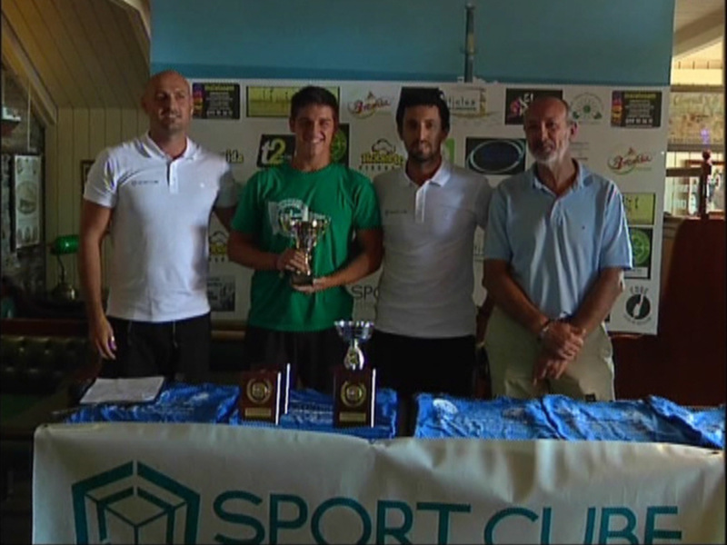Cuatro personas posan con un trofeo en un evento deportivo, con un cartel de 'Sport Club' en la mesa delante de ellos.