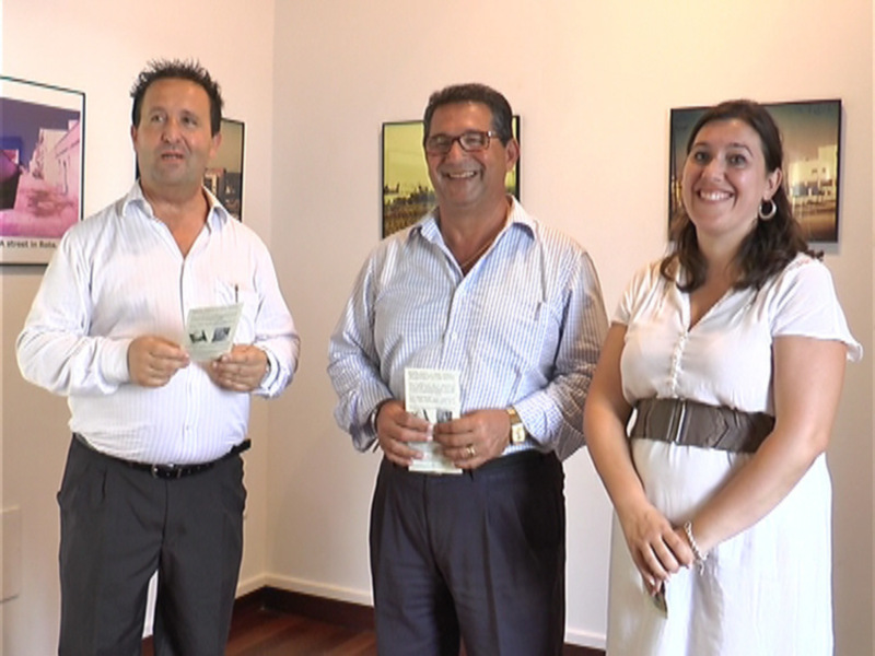 Tres personas sonrientes posando juntas en un espacio interior con obras de arte en las paredes.