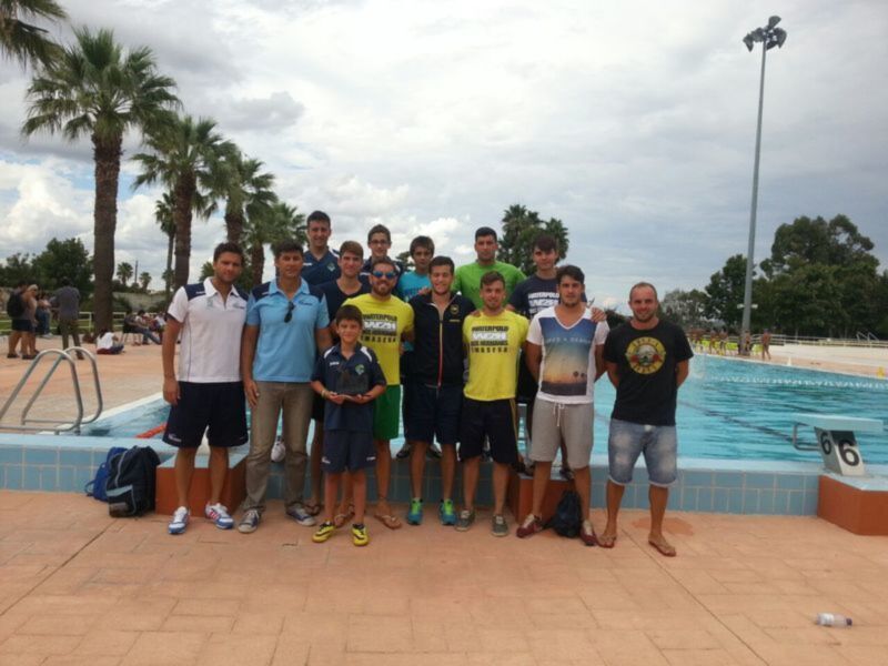 Equipo de natación posando junto a la piscina al aire libre.