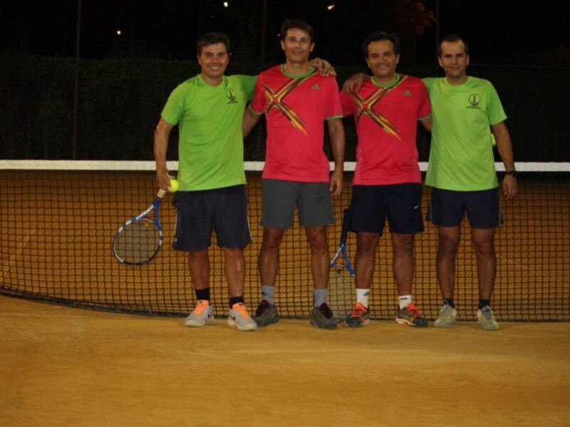 Equipo de tenis posando juntos en una cancha de noche.