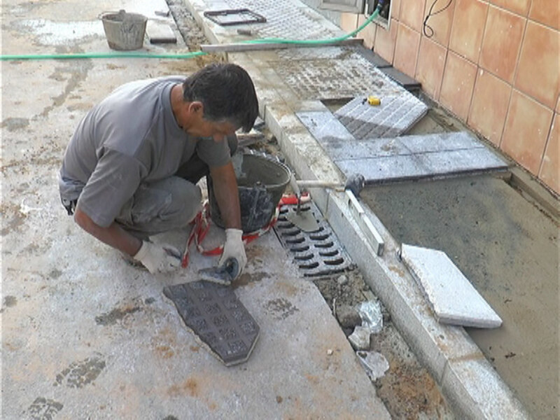Trabajador colocando baldosas en una obra de construcción.