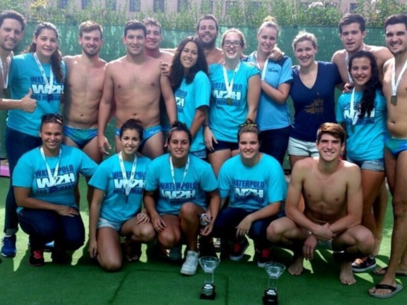 Equipo de waterpolo celebrando con medallas y trofeos tras un partido exitoso.