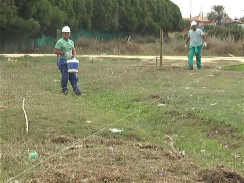Trabajadores en un campo con herramientas y materiales, preparando o inspeccionando una zona.