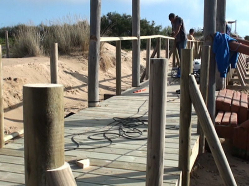 Construction site on a sandy beach with wooden planks and tools.
