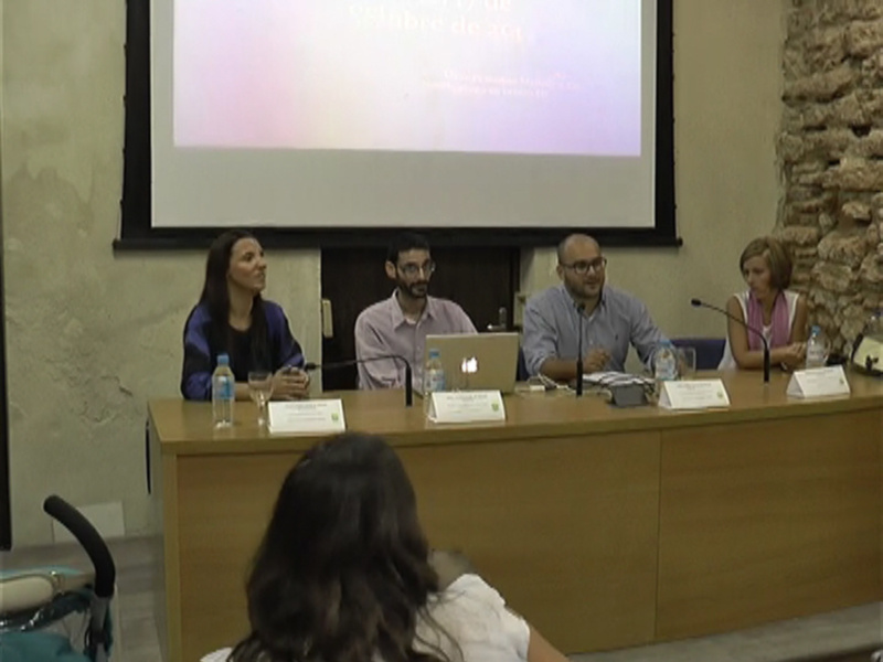 Panel de discusión en una conferencia con proyección en el fondo.