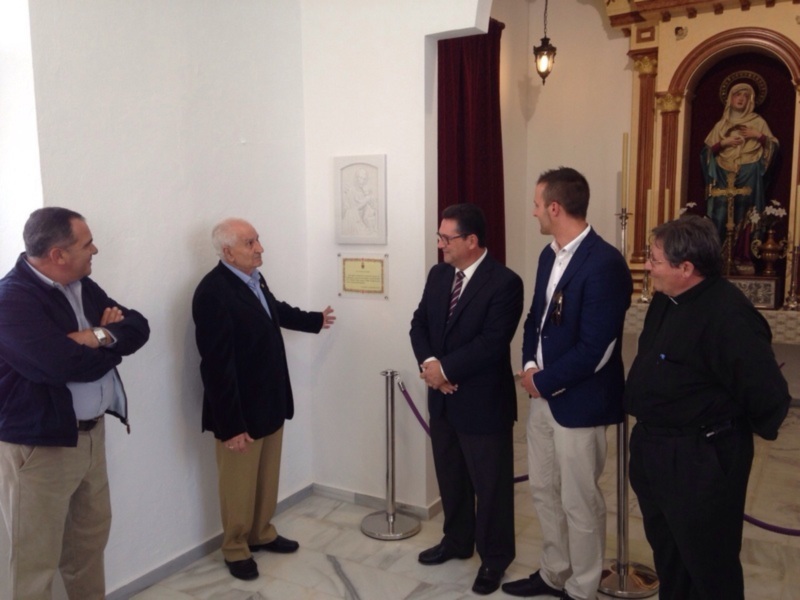 Personas en una sala con una imagen religiosa en el fondo, intercambiando ideas.