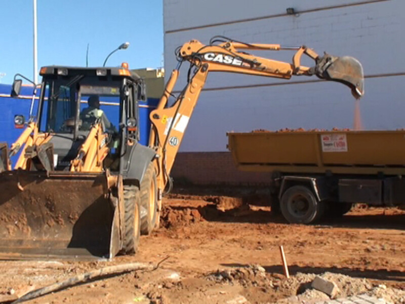 Excavadora CASE cargando materiales en un camión de volteo en una obra de construcción.