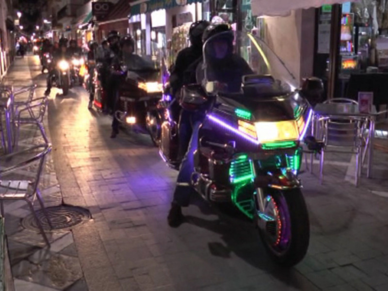 Motociclistas con luces brillantes en una calle nocturna animada.