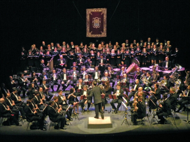 Orquesta y coro en escenario durante un concierto formal.