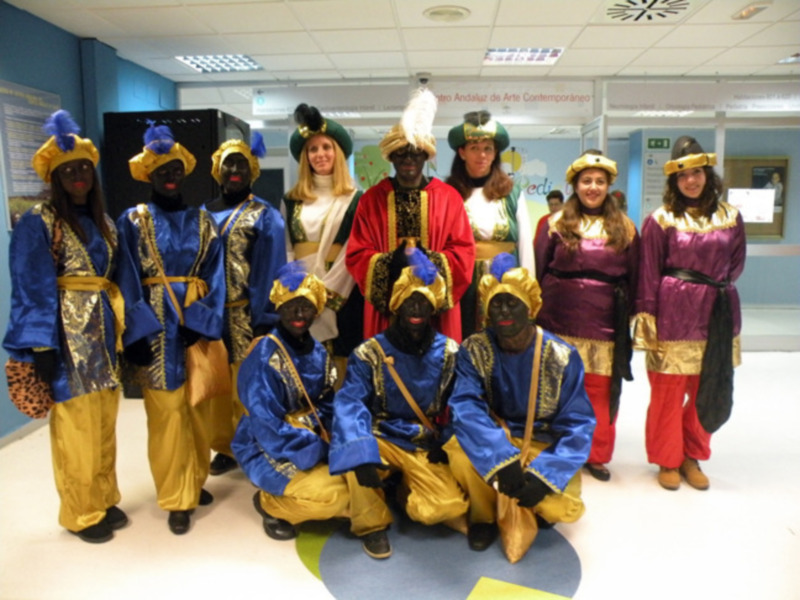 Grupo de personas vestidas con trajes tradicionales posando en un espacio interior.