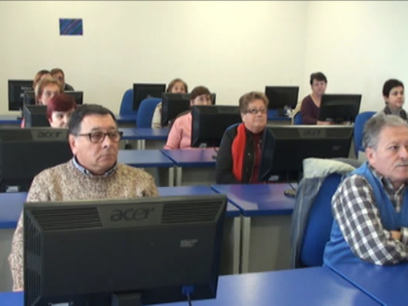 Clase de informática para adultos en una sala de computadoras.