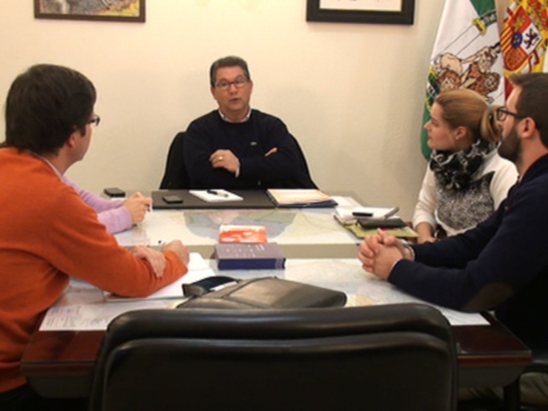 Reunión de trabajo en una oficina con documentos y mapas sobre la mesa.