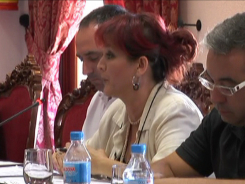 Reunión de trabajo con participantes sentados en una mesa, microfonos y botellas de agua en el centro.