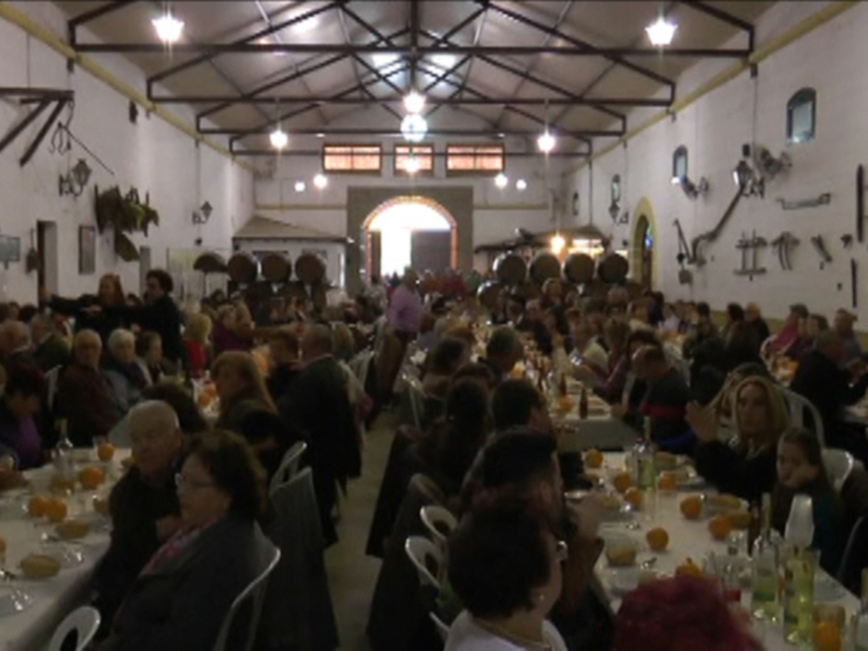 Fiesta en una gran sala con mesas llenas de comidas y bebidas, personas disfrutando en un ambiente festivo.