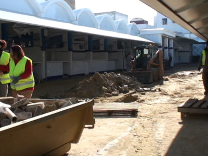 Trabajadores en chalecos reflectantes realizan tareas de limpieza y desmonte en un mercado.