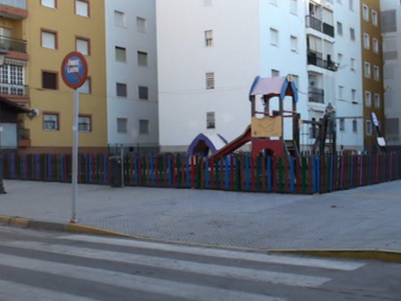 Área de juegos infantiles junto a edificios residenciales en una zona urbana.