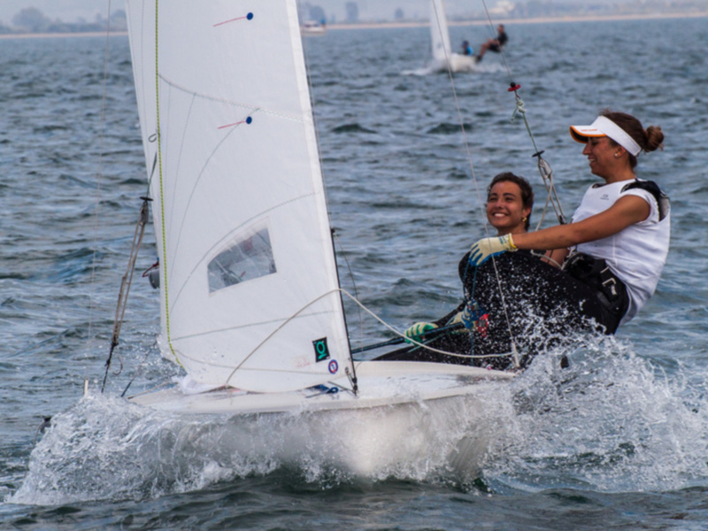 Dos atletas disfrutan de una carrera de vela en el mar, mostrando habilidad y emoción en medio de las olas.