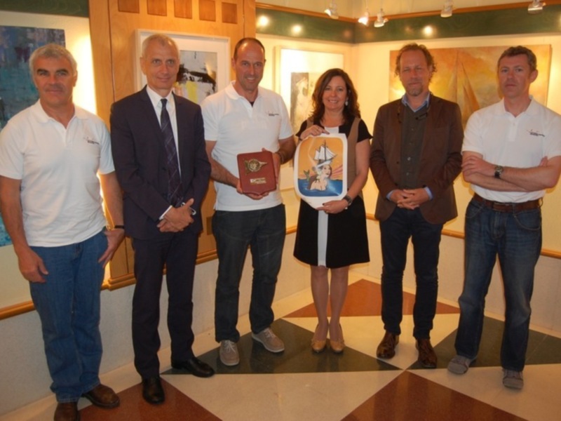 Un grupo de personas posa para una foto en un espacio con obras de arte en la pared.