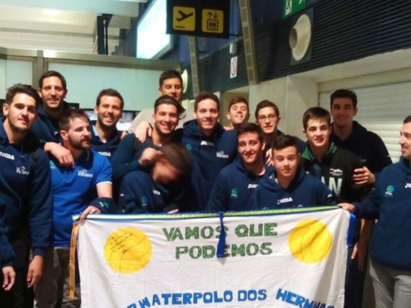 Equipo de waterpolo posando con su bandera en el aeropuerto.