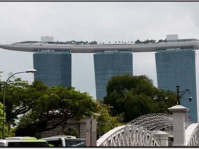 Vista del Marina Bay Sands en Singapur, destacando su arquitectura moderna y los árboles en primer plano.