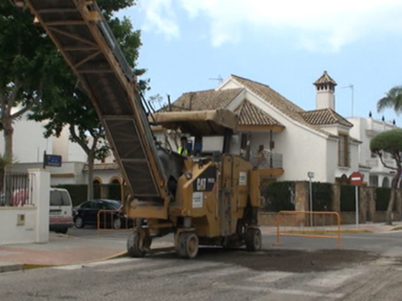 Máquina de construcción trabajando en la reparación de una carretera en una zona residencial.
