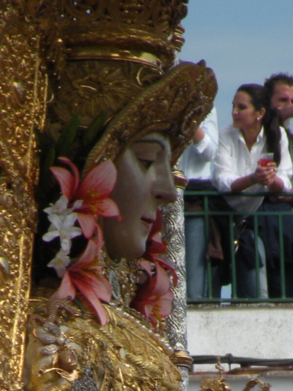 Estatua dorada con detalles florales y un fondo de personas observando.