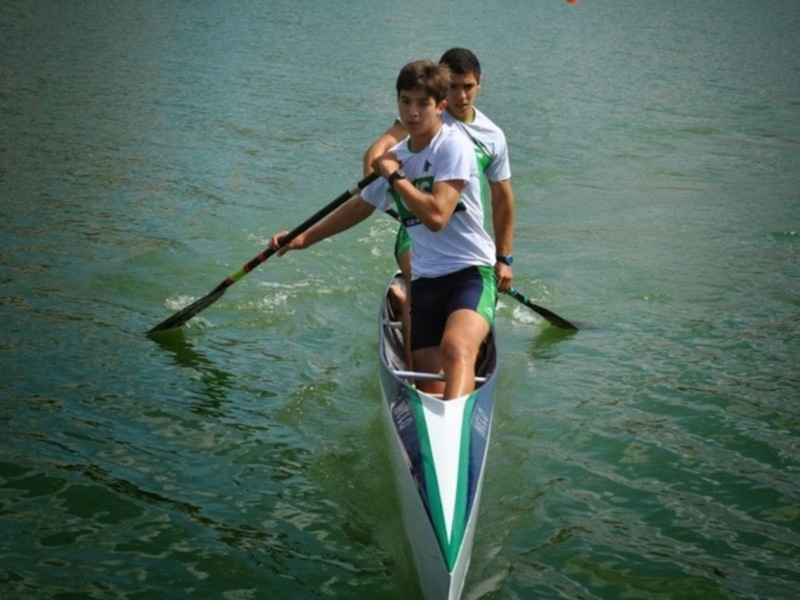 Dos jóvenes competidores en un canoa durante una regata en el agua.