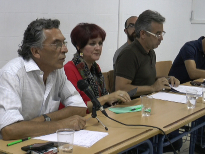 Reunión de trabajo en una sala de conferencias con participantes sentados alrededor de una mesa.