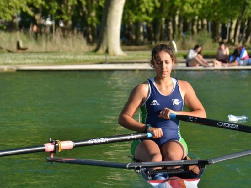 Atleta de remo en acción durante un entrenamiento en un río tranquilo.