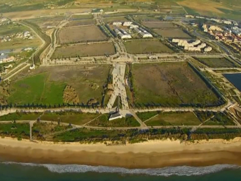 Vista aérea de un área costera con infraestructuras urbanas y una playa al borde del océano.