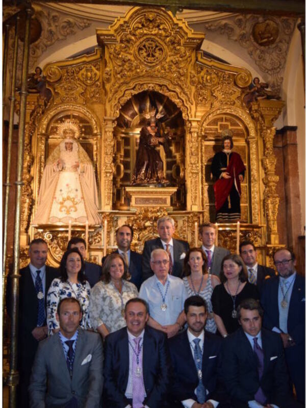 Grupo de personas posando en frente de un altar ornamental en un entorno religioso.