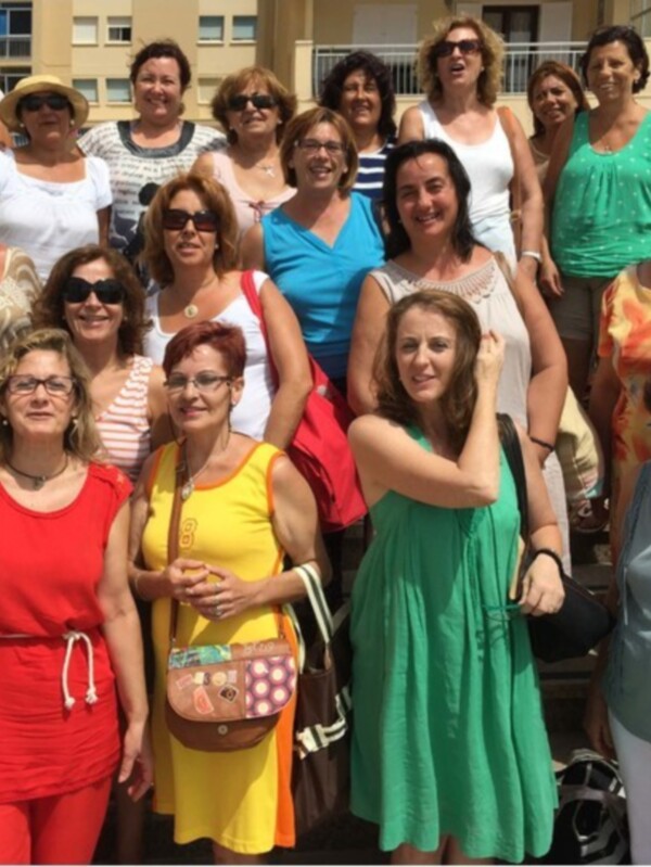 Grande grupo de mujeres sonrientes posando juntas en un día soleado.