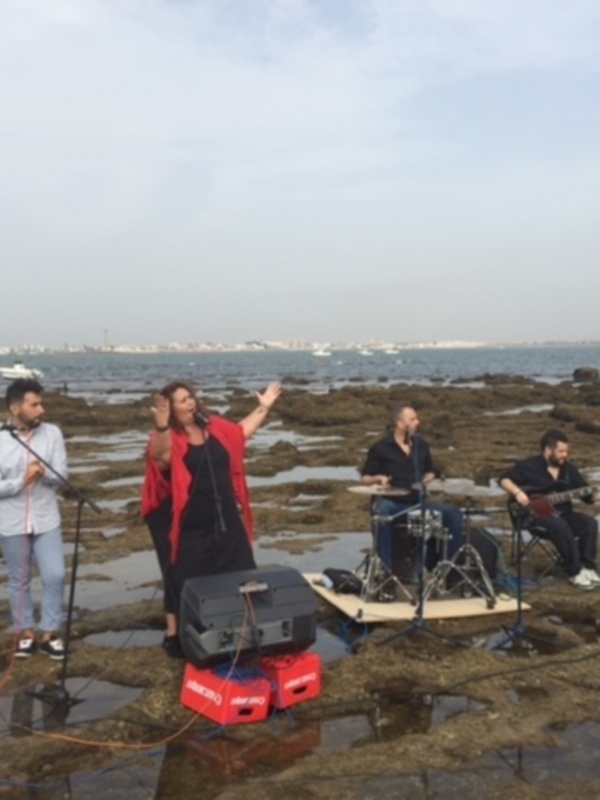 Músicos en la playa, disfrutando del mar y la música en un día soleado.
