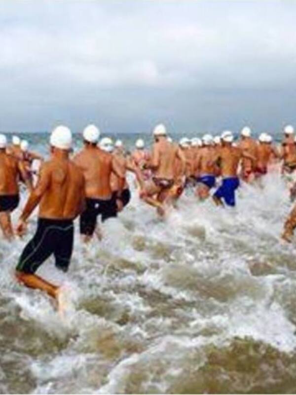 Atletas corriendo en la playa durante un triatlón.
