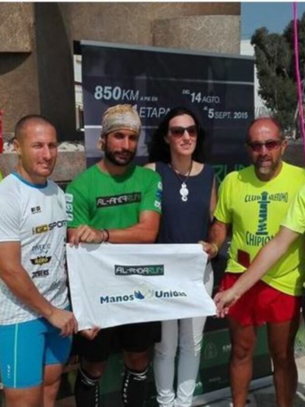 Equipo de atletas posando con una bandera de Manos Unidas en Chipiona, España.